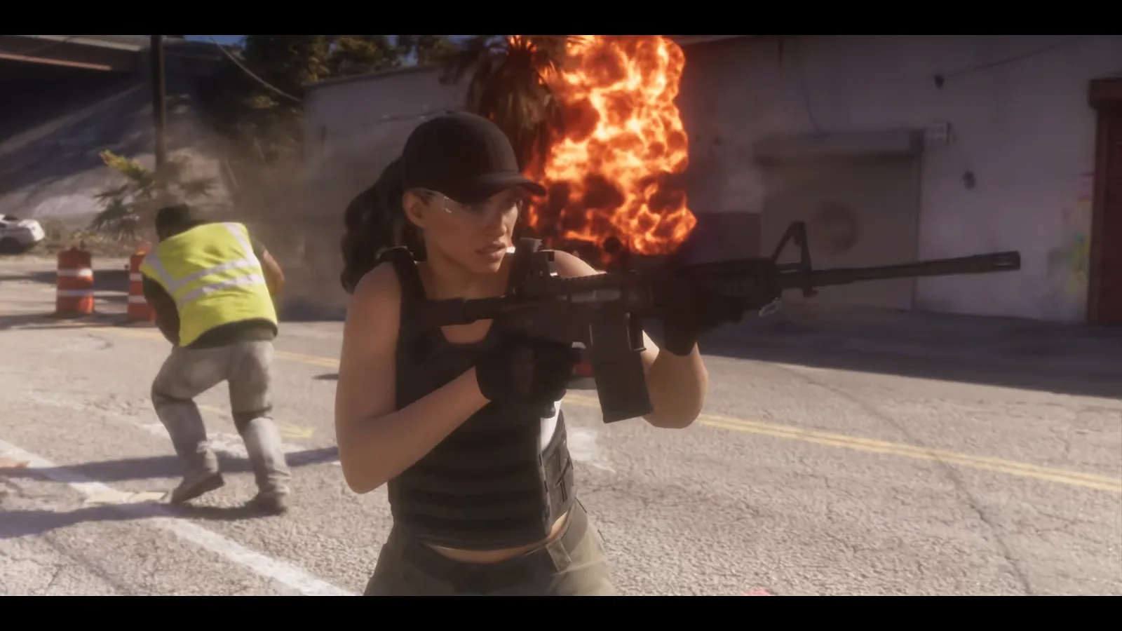 GTA 6 Launch Trailer: a woman in a cap, safety glasses and a plate carrier aims an AR-style carbine, a man in a hi-vis vest and a fire behind her