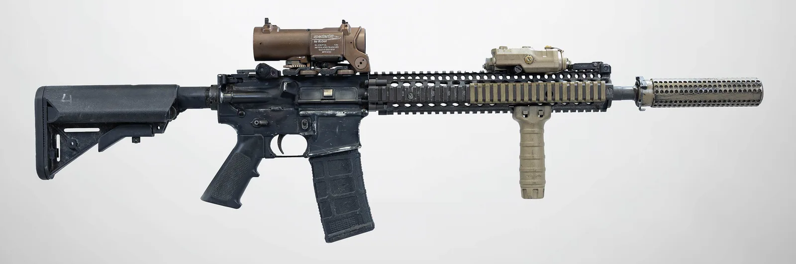 A real M4A1 SOPMOD Block II carbine with a suppressor, optic and foregrip, left side view, on a light grey background