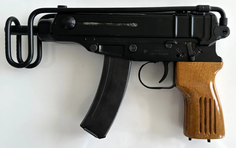 A real Czech Škorpion vz. 61 submachine gun with wooden grip and folded wire stock, right side view, on white