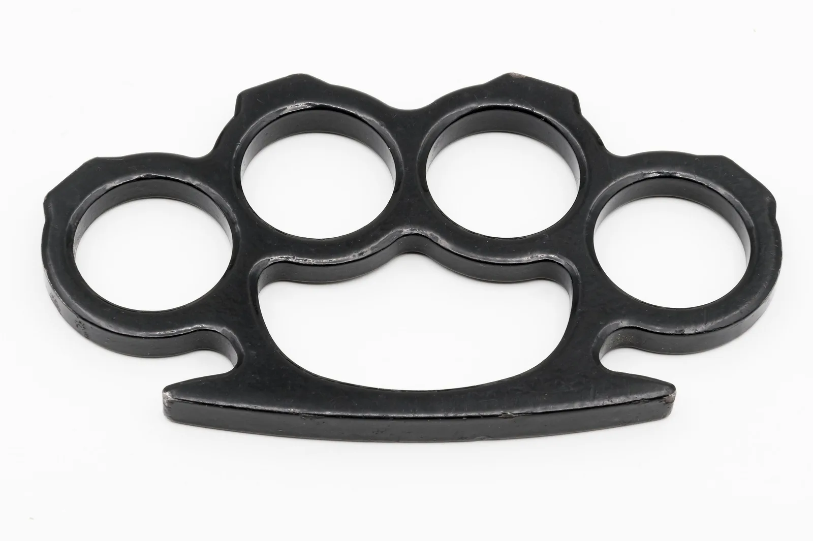 A real set of black metal brass knuckles with four finger rings, flat view on a plain white background