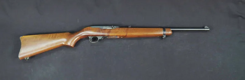 A real Ruger 10/22 .22 rimfire carbine with a wooden stock, right side view, Smithsonian photo on a dark background