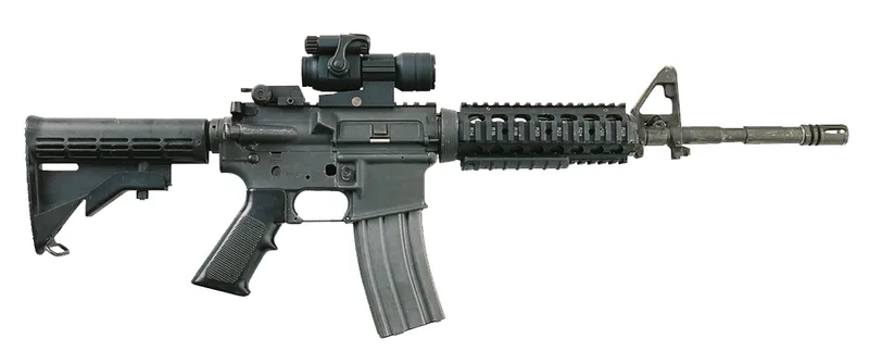 A real M4A1 flat-top carbine with a rail handguard and red-dot sight, left side view, on a grey background