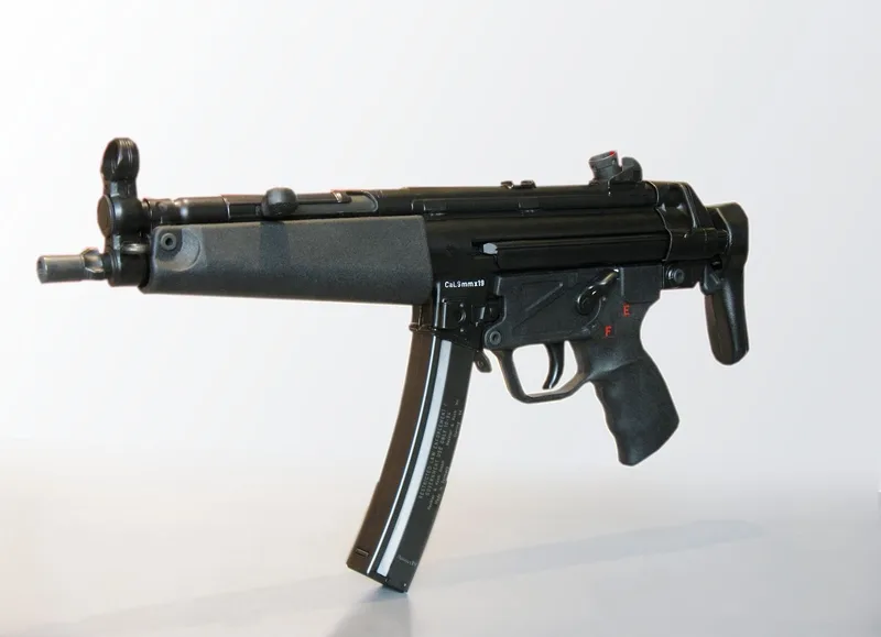 A real Heckler & Koch MP5 9mm submachine gun without a stock, left side view, on a light grey background