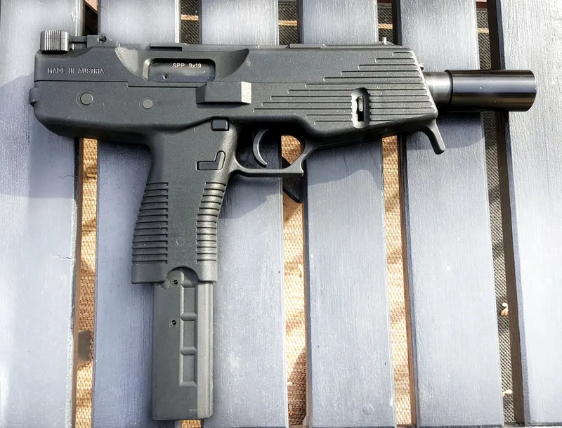 A real Steyr SPP 9mm pistol with a 30-round magazine, left side view, laid on white wooden slats